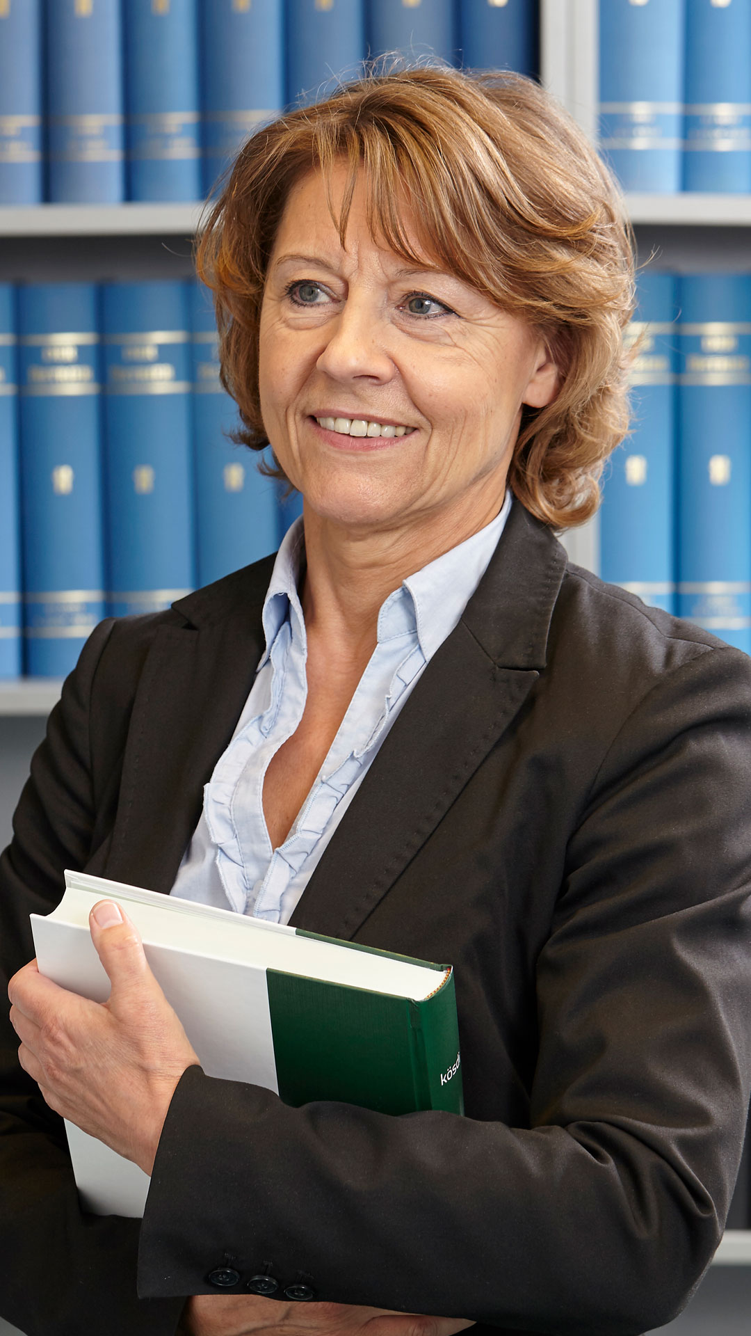 kanzlei_mueller Steuerberaterin Brigitte Müller steht vor einem Schrank mit Büchern