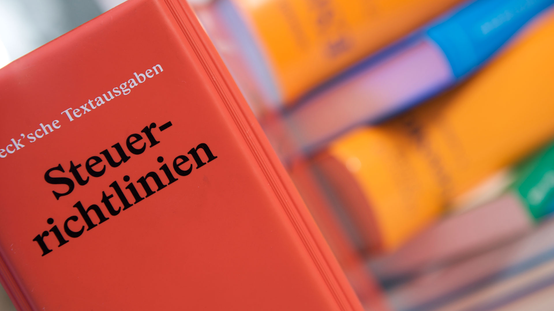 Bücher auf einem Schreibtisch. Im Vordergrund das Buch: Steuerrichtlinien